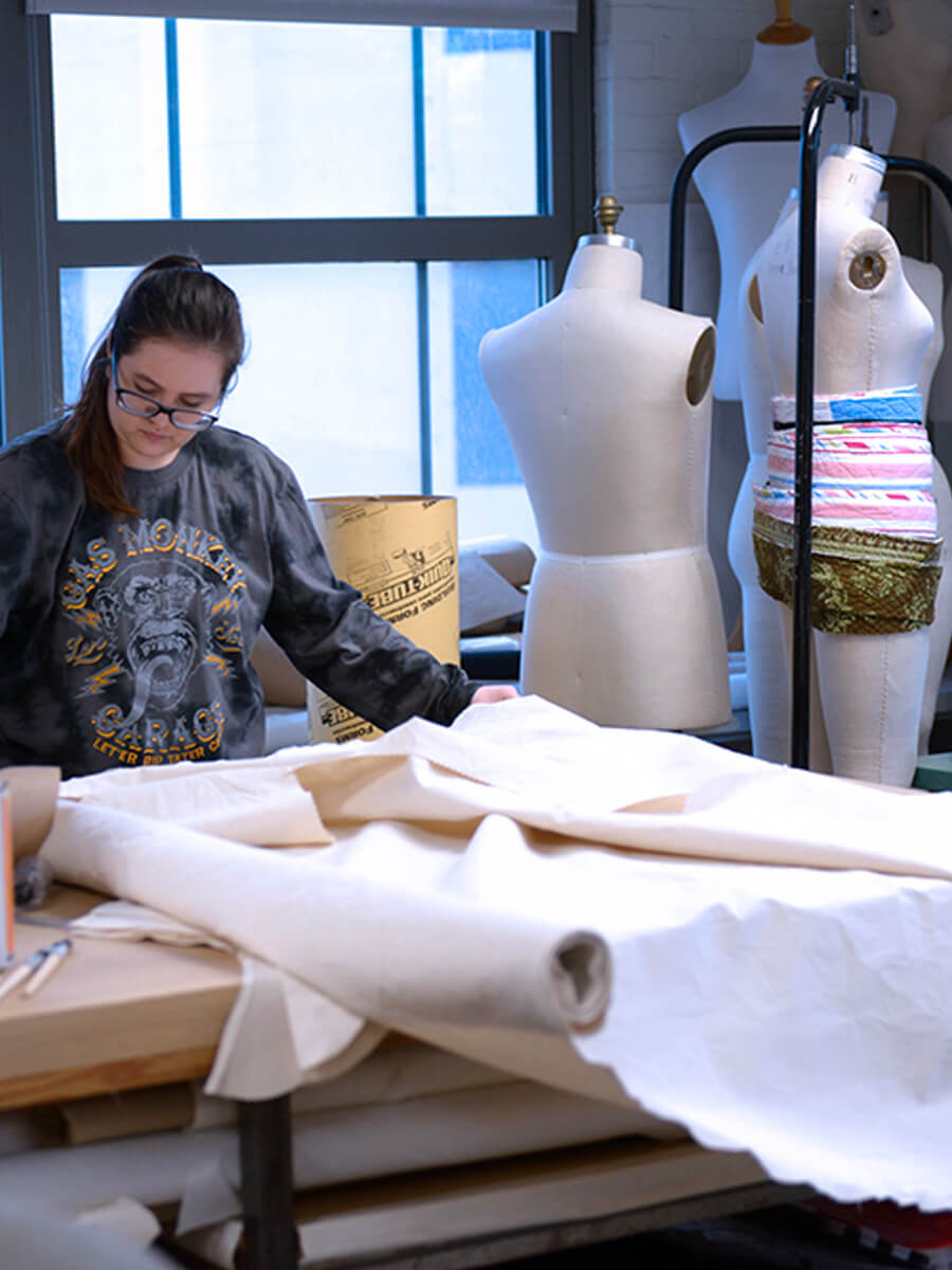 person working with fabric in costume design studio