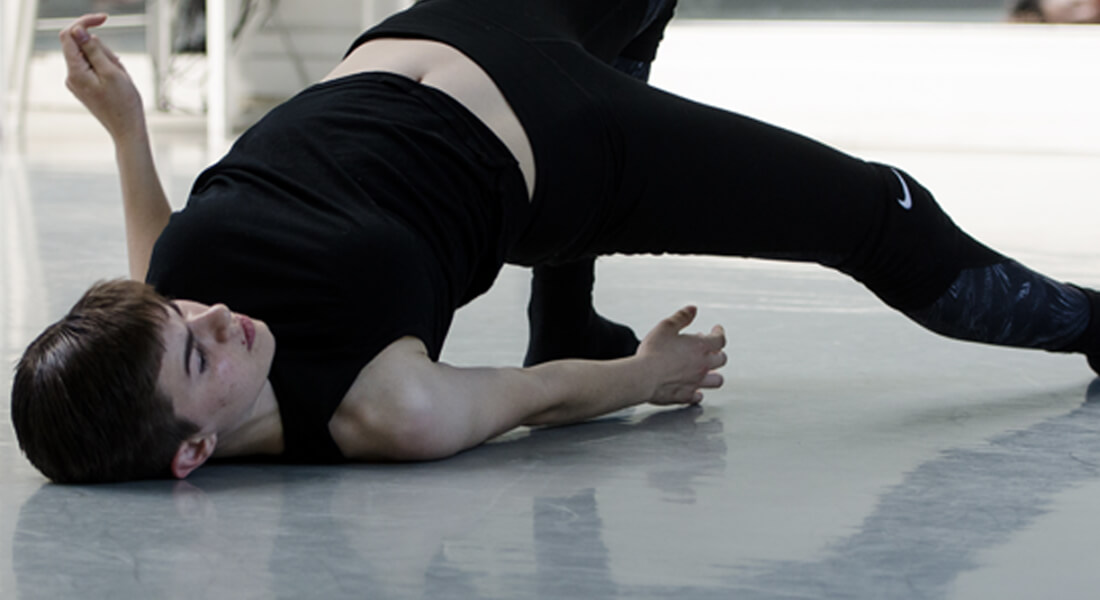 teen practicing improvisational move on floor