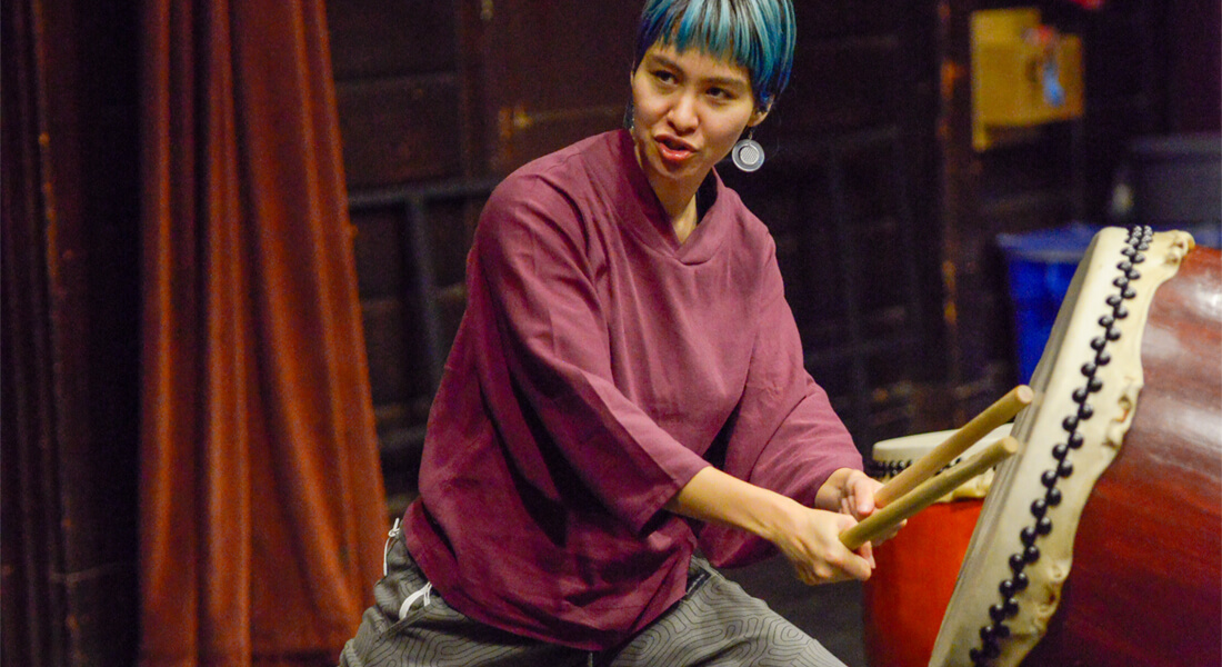 woman of Asian descent demonstrating taiko drums